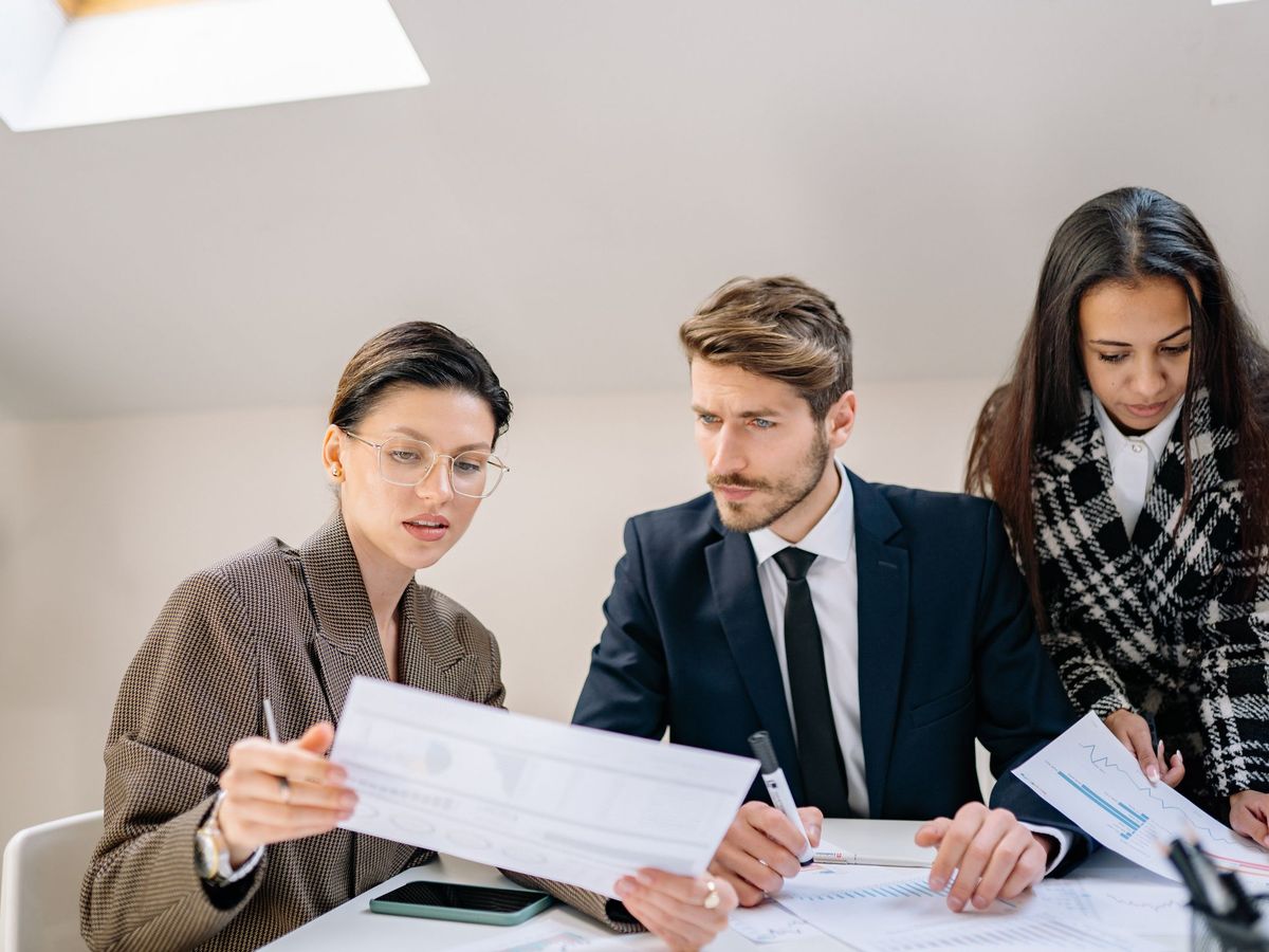Three colleagues reviewing printed charts and documents together at a table